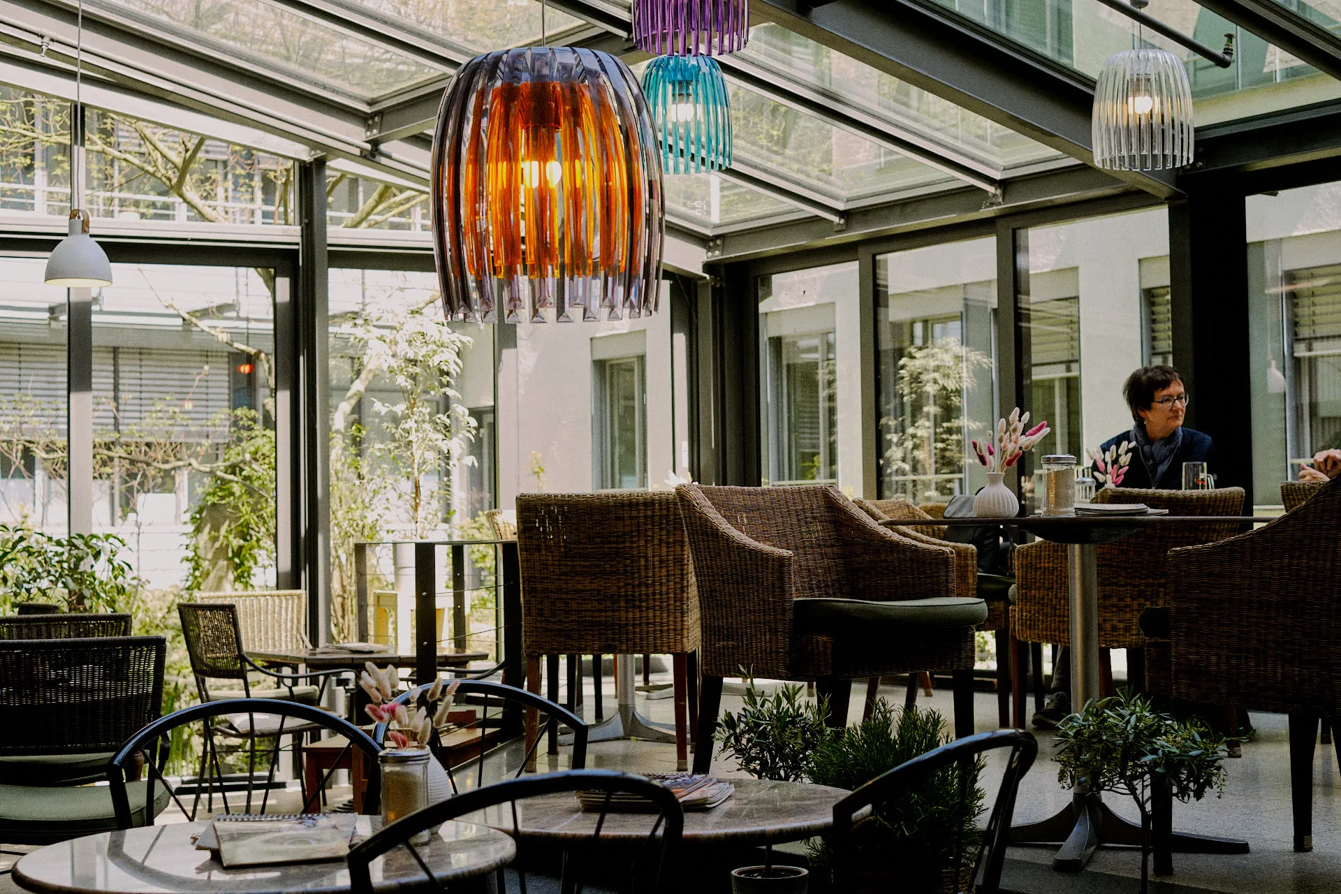 Wintergarten mit bunten Pendant-Lampen und gemütlichen Korbsesseln